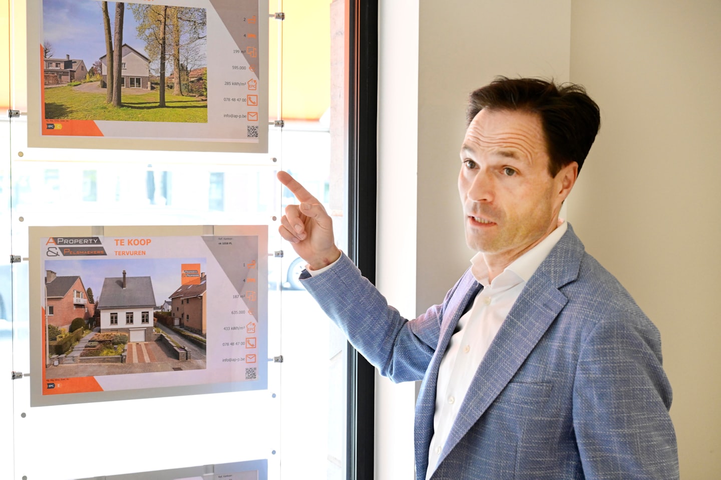 Man points to real estate listings on a digital display.